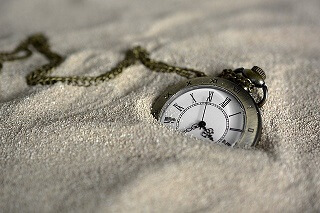 砂に埋もれた時計の写真